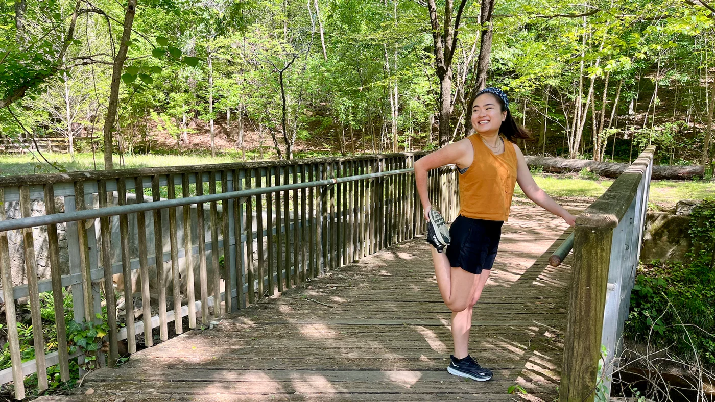 Woman stretching on a wooded trail before a workout